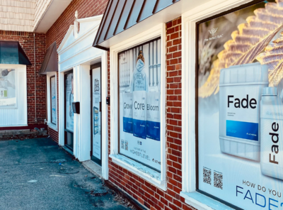 Storefront windows using perforated vinyl graphics to advertise their brand. Printed and installed by Atlas Wrap Co.